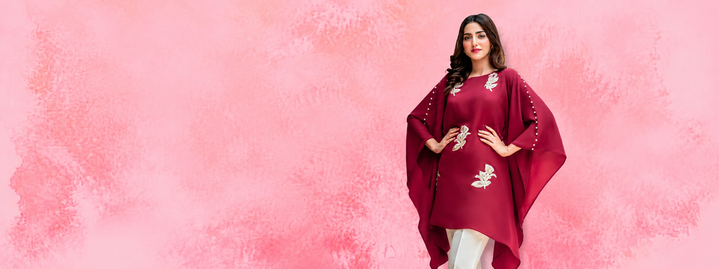 Woman in maroon embroidered kaftan against soft pink textured watercolor background